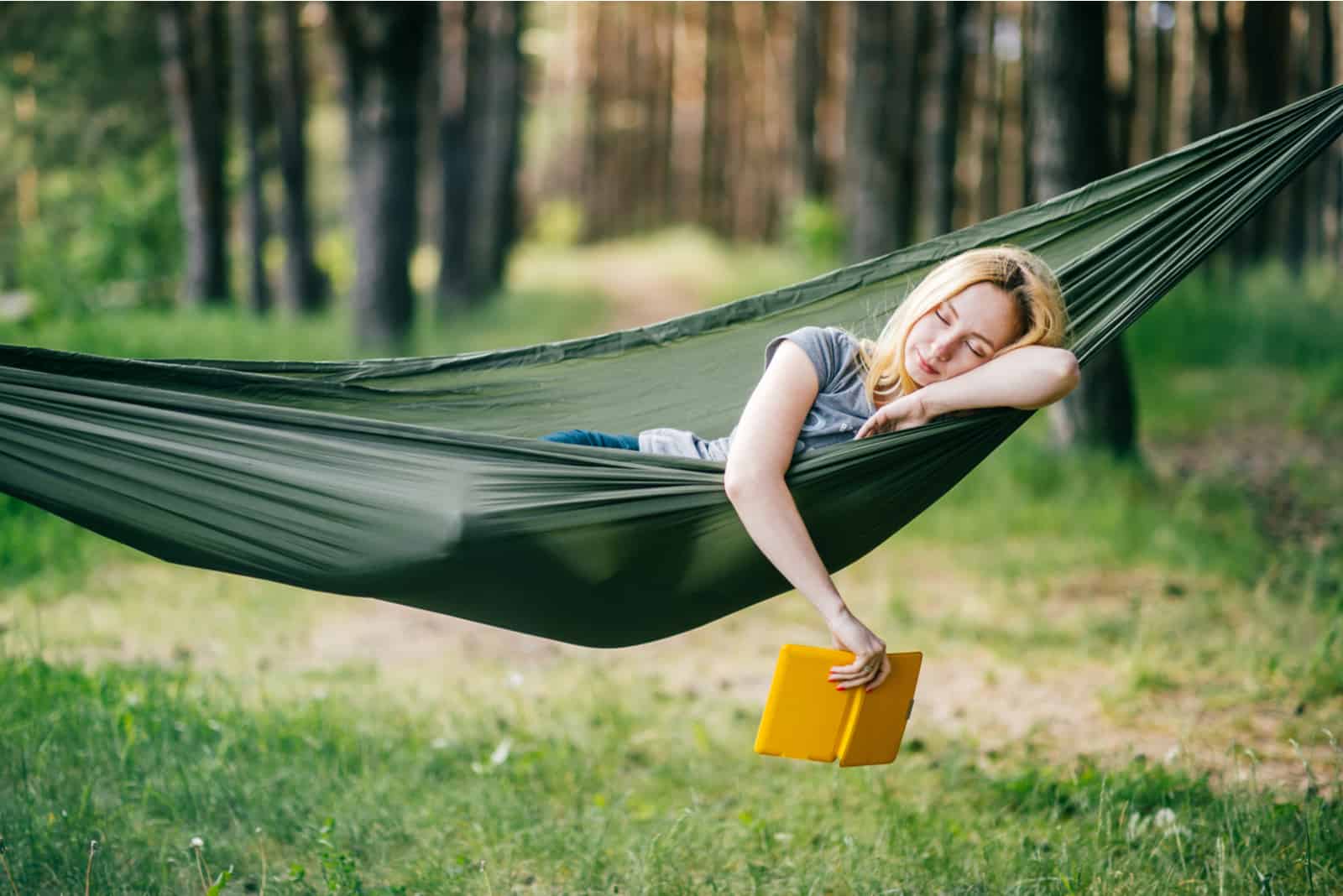 young blonde reading a book in a hammock