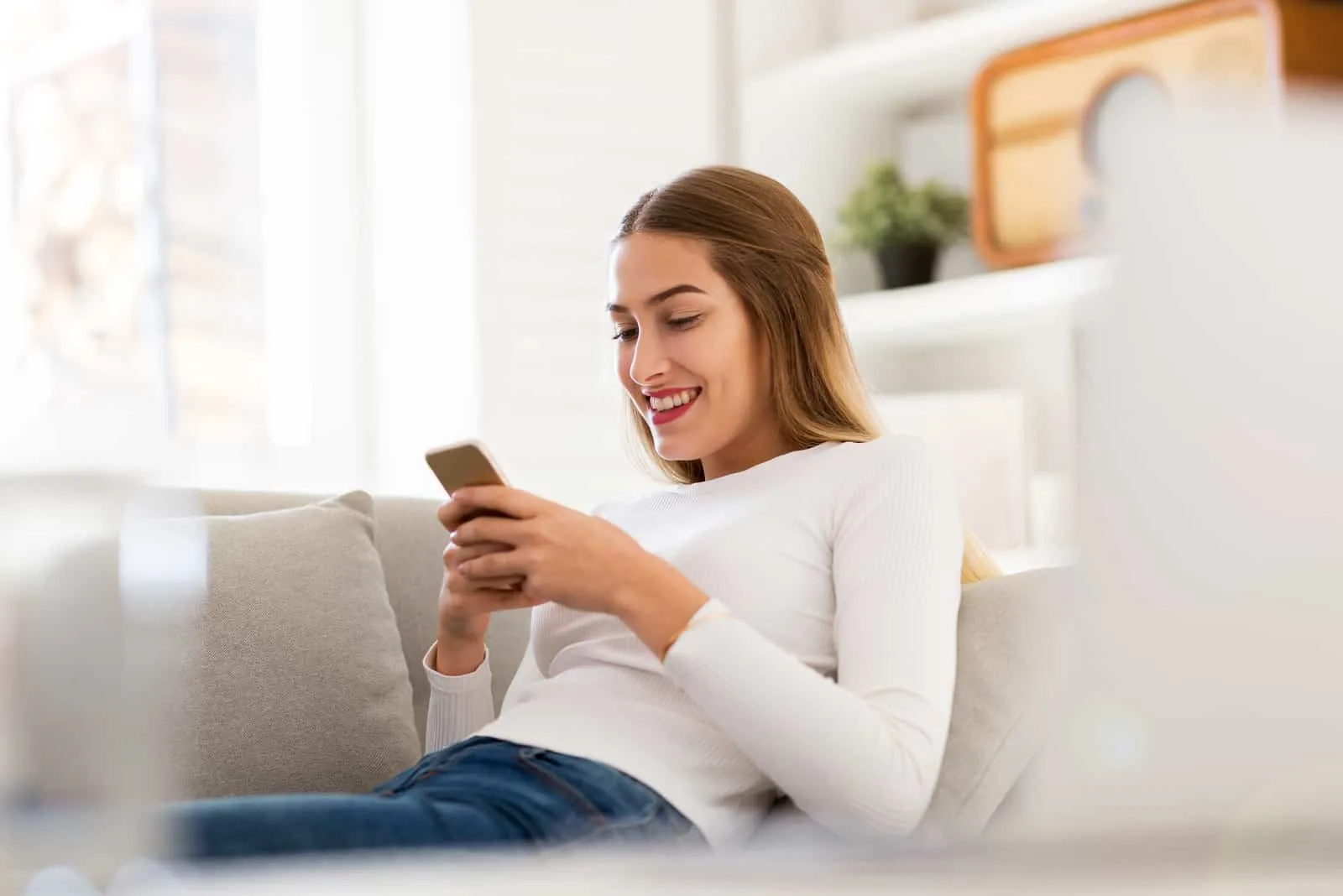 young woman sitting on sofa looking at her phone