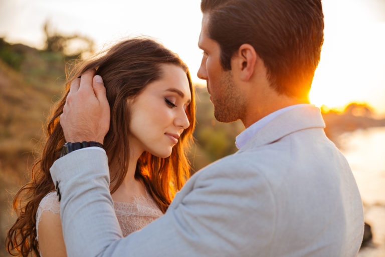 man caresing woman's hair at sunset