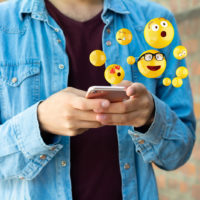 homem a enviar emojis através do telemóvel