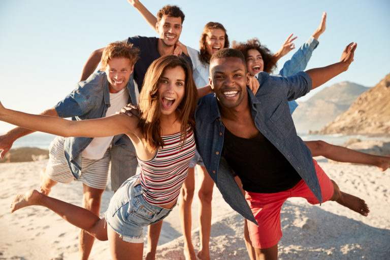 cheerful friends posing on beach at sunny day