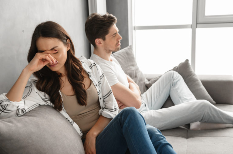 casal em relação forçada sentado num sofá
