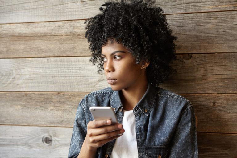 serious young woman holding mobile phone and looking at distance
