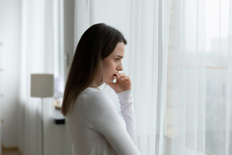 mujer preocupada mirando por la ventana