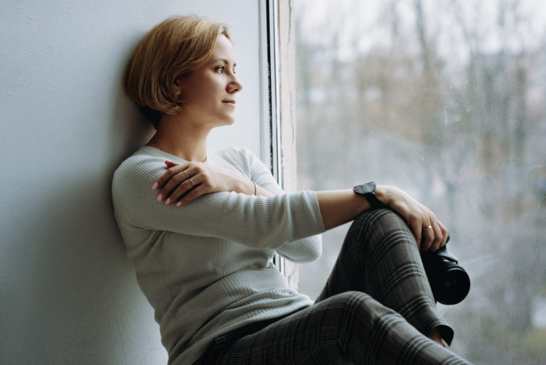 woman holding camera looking through window