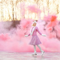 mulher a patinar com fumo cor-de-rosa atrás de si