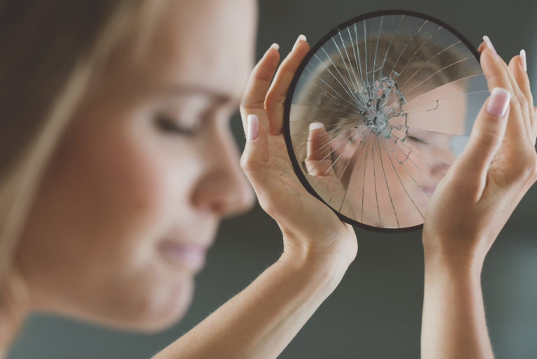 woman holding a shattered mirror