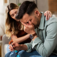 hombre llorando mientras su novia le consuela