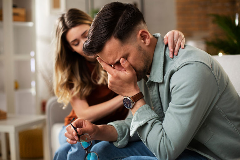 man crying while girlfriend comforts him