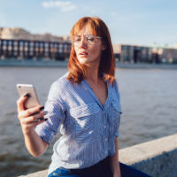 woman standing outside with phone in hand