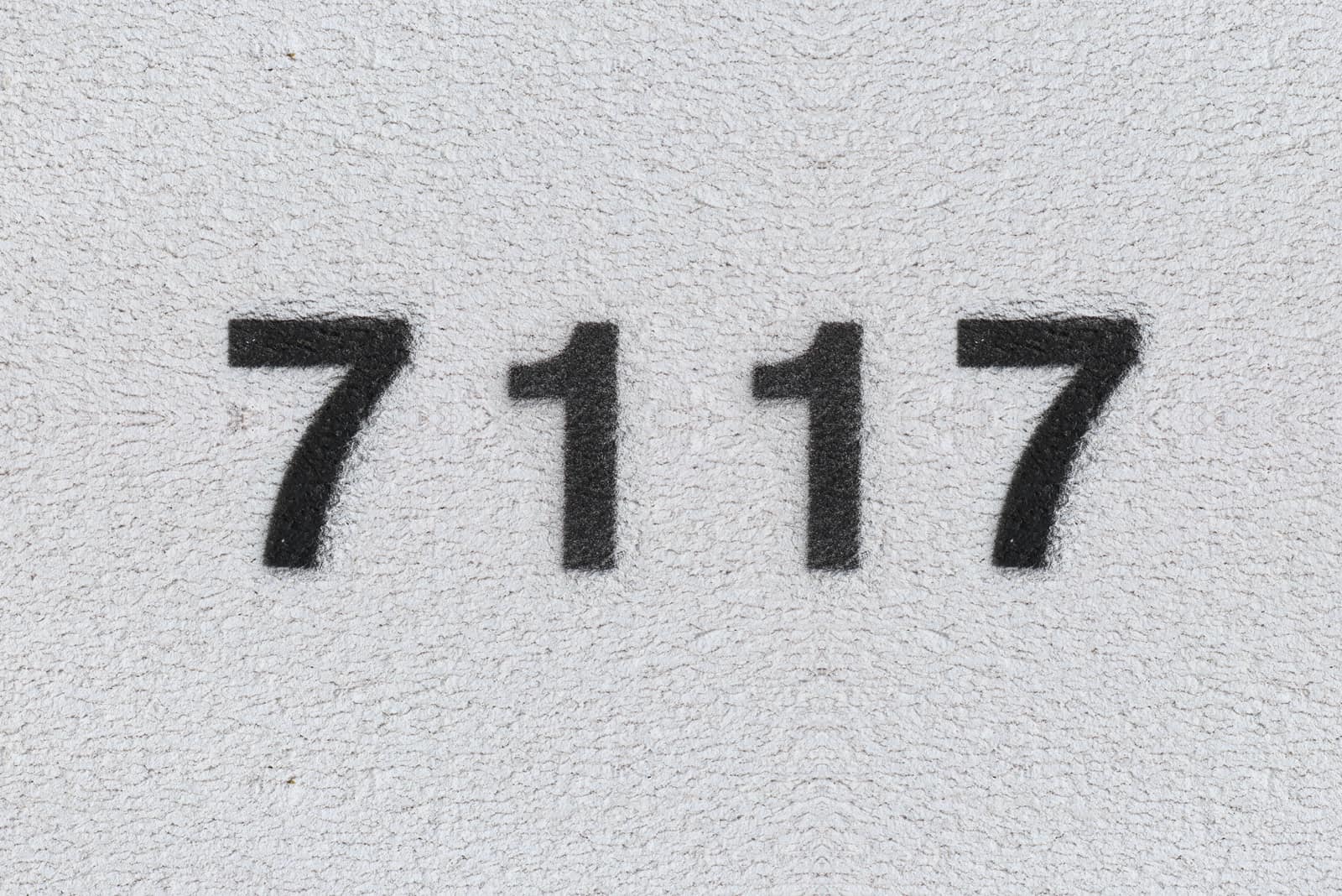 black number 7117 on grey wall