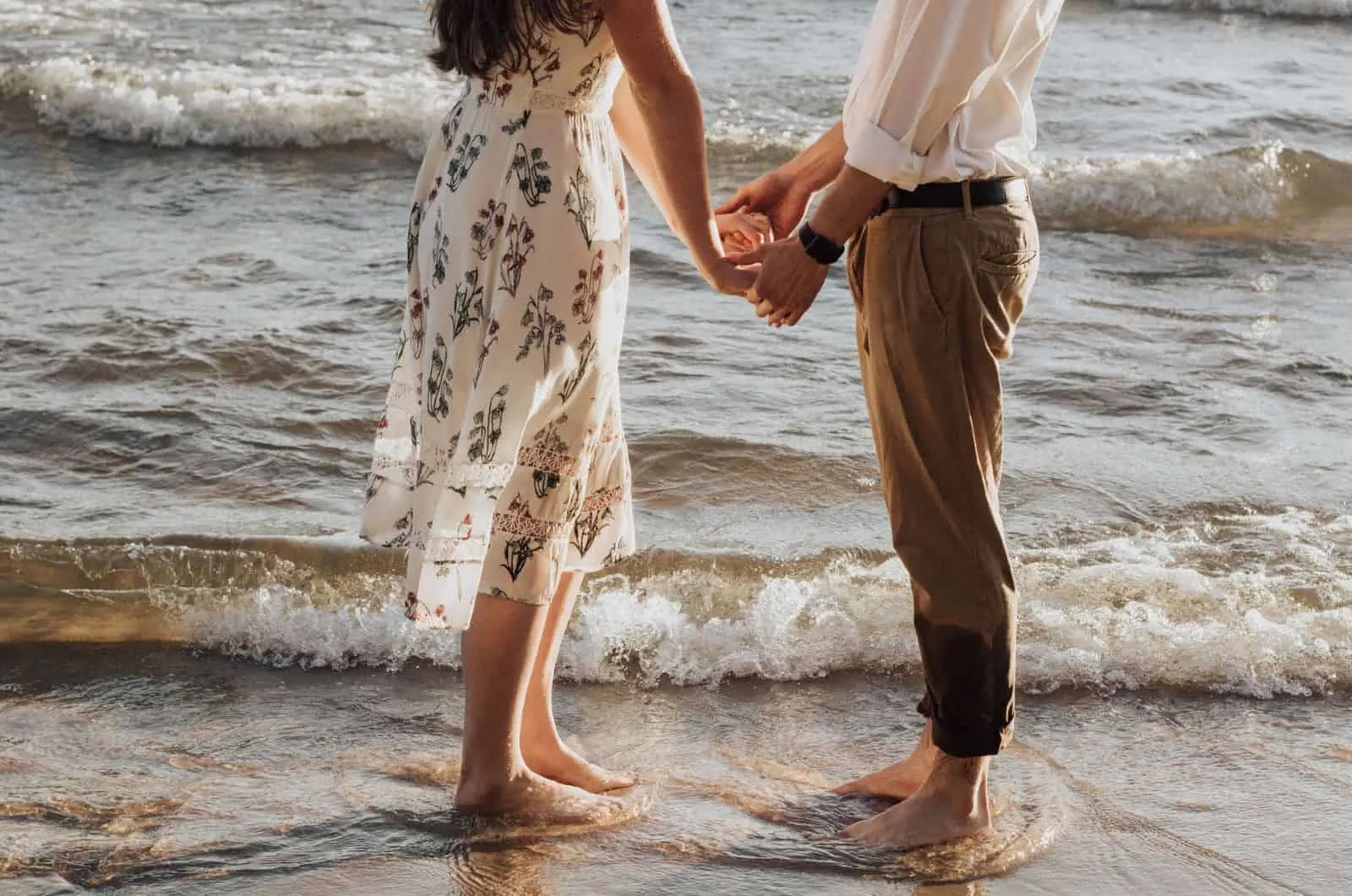 couple holding hands in front of the sea