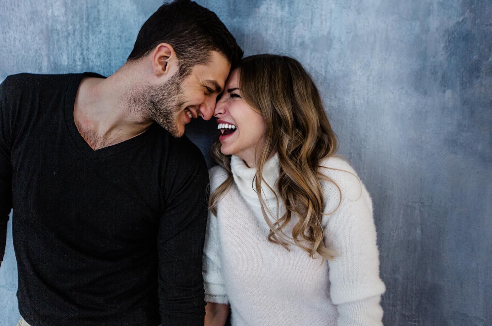 couple laughing with blue background