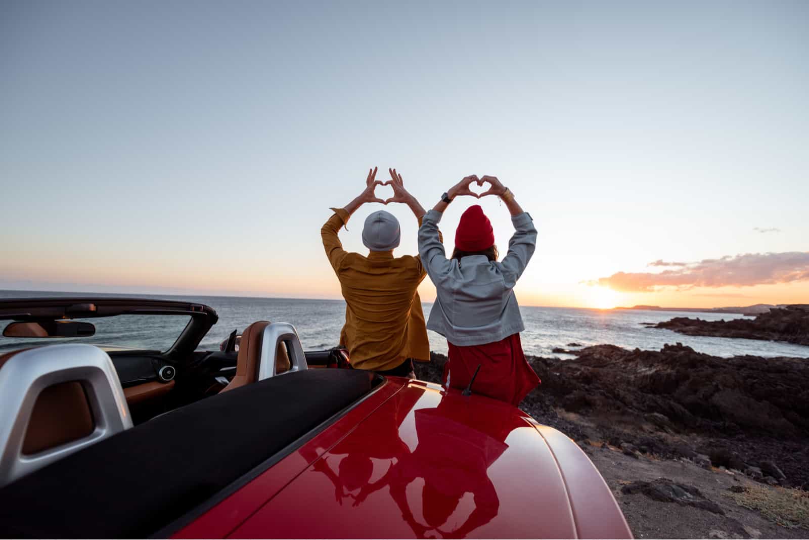 pareja hizo forma de corazón con las manos cerca de la costa