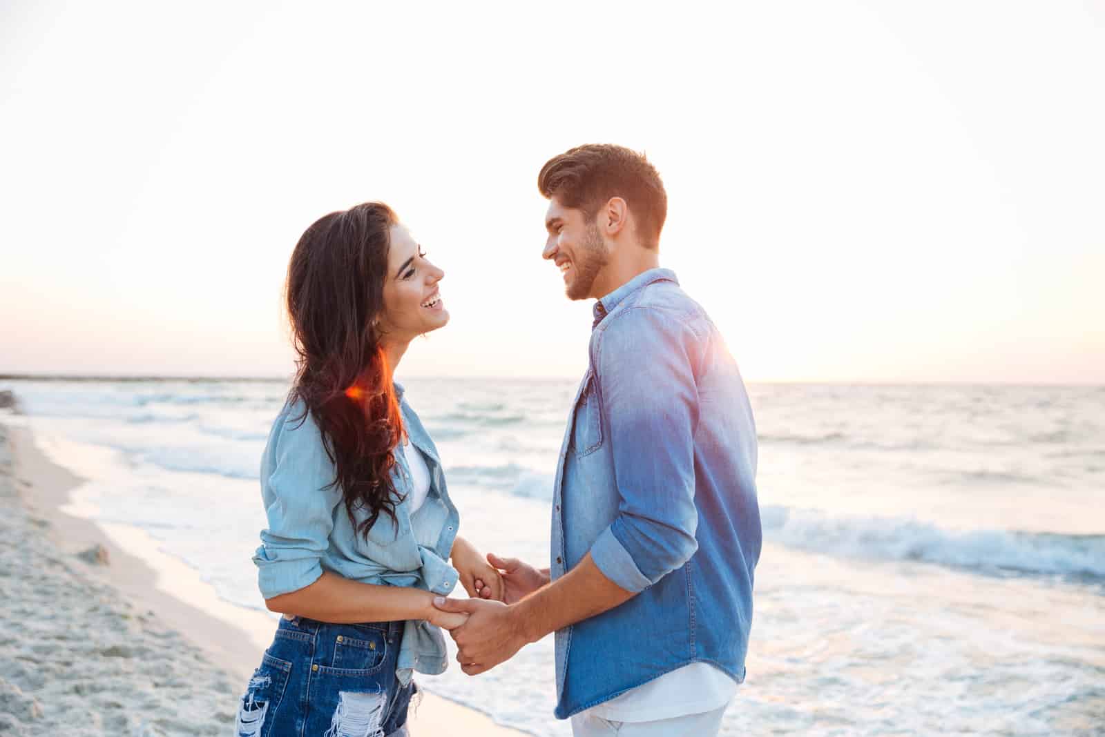 pareja feliz cogida de la mano en la playa