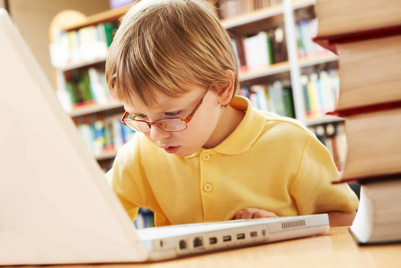 little boy with glasses typing on laptop