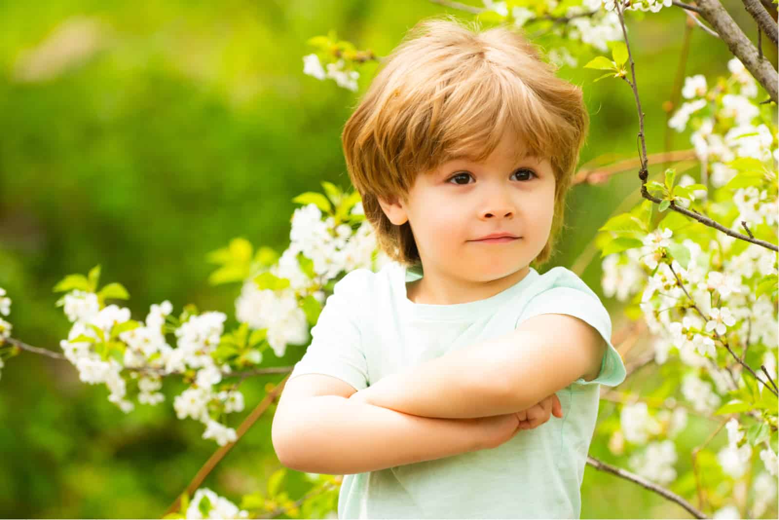 niño confiado de pie al aire libre con los brazos cruzados