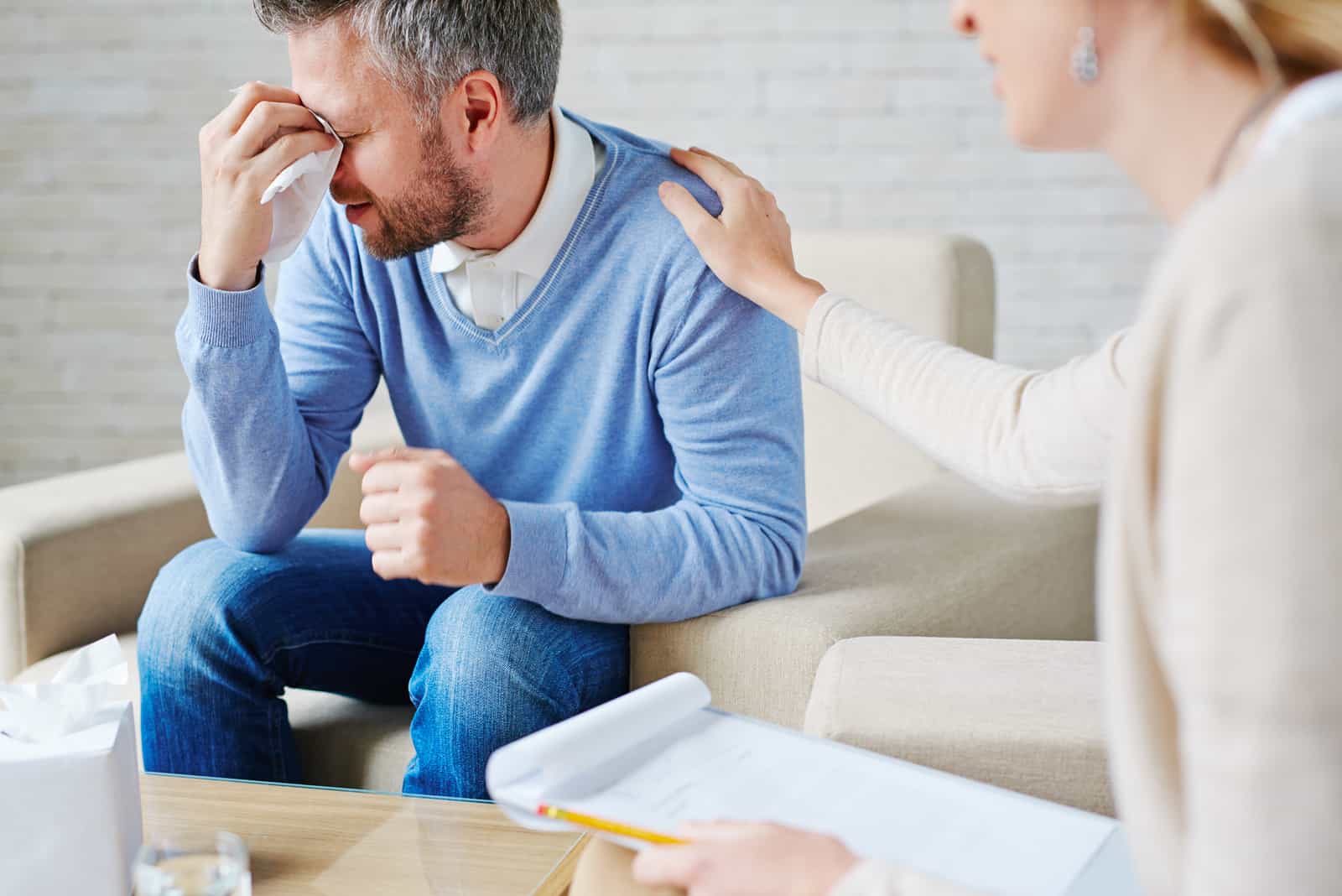 uomo che piange mentre la moglie lo consola