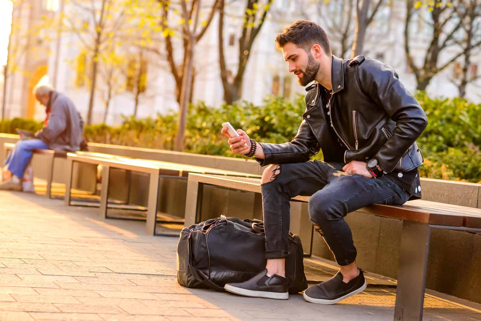 man sitting on bench in park texting