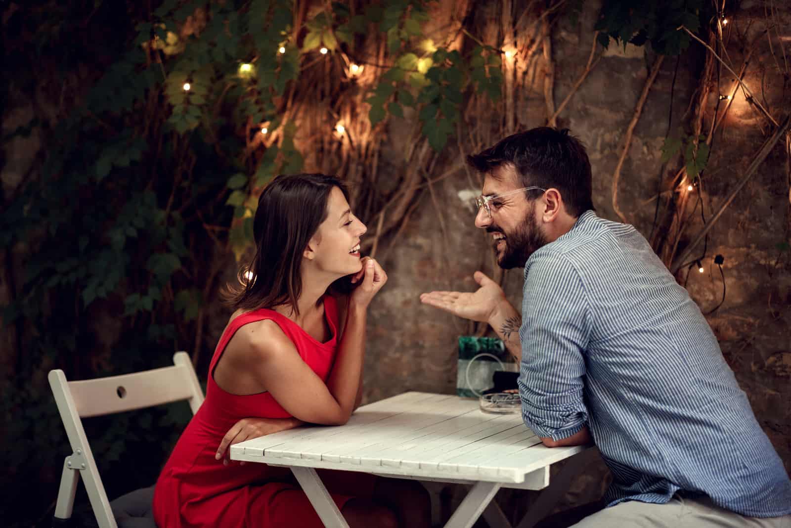 pareja sonriente coqueteando junto a la mesa