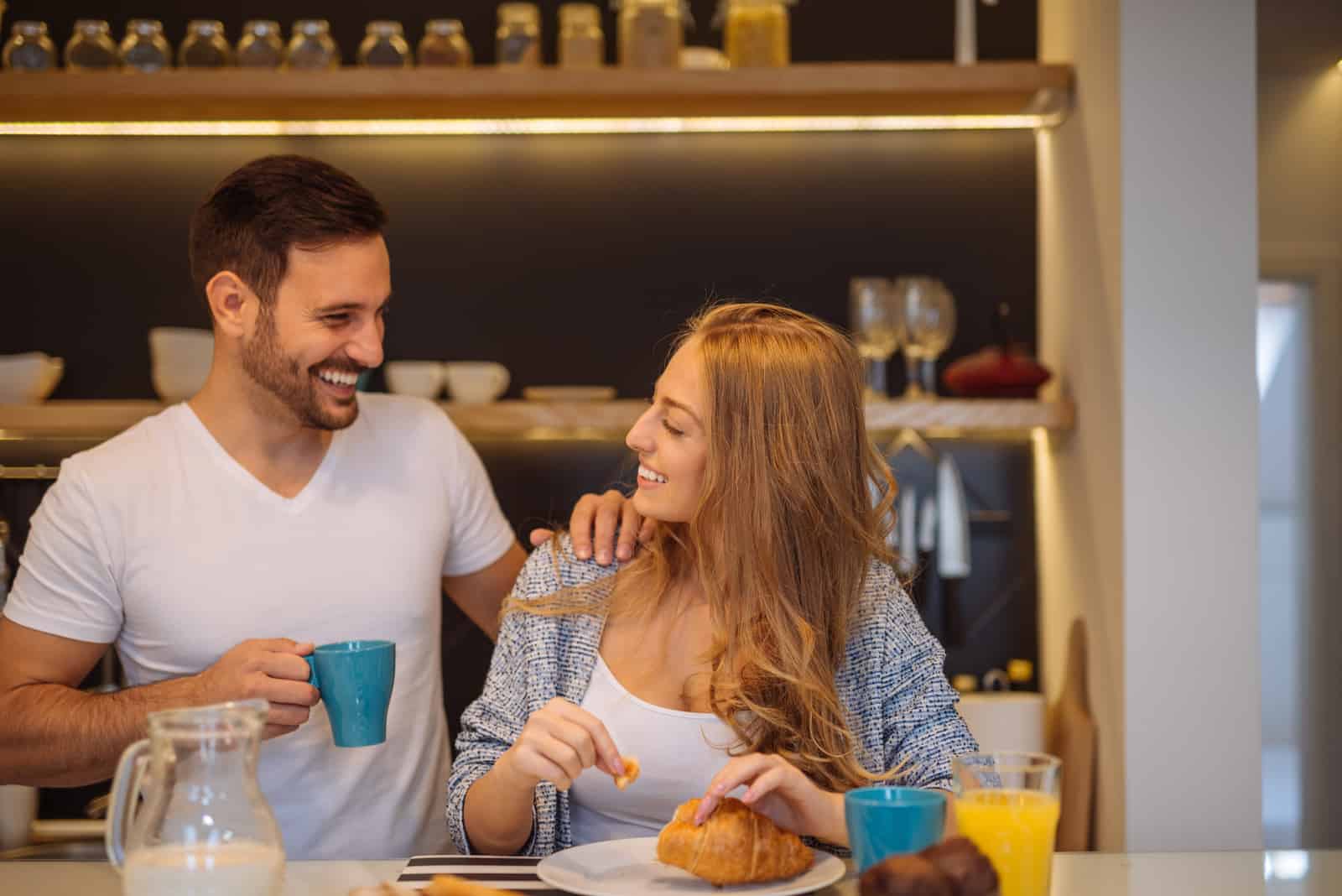 coppia sorridente che parla mentre fa colazione in cucina