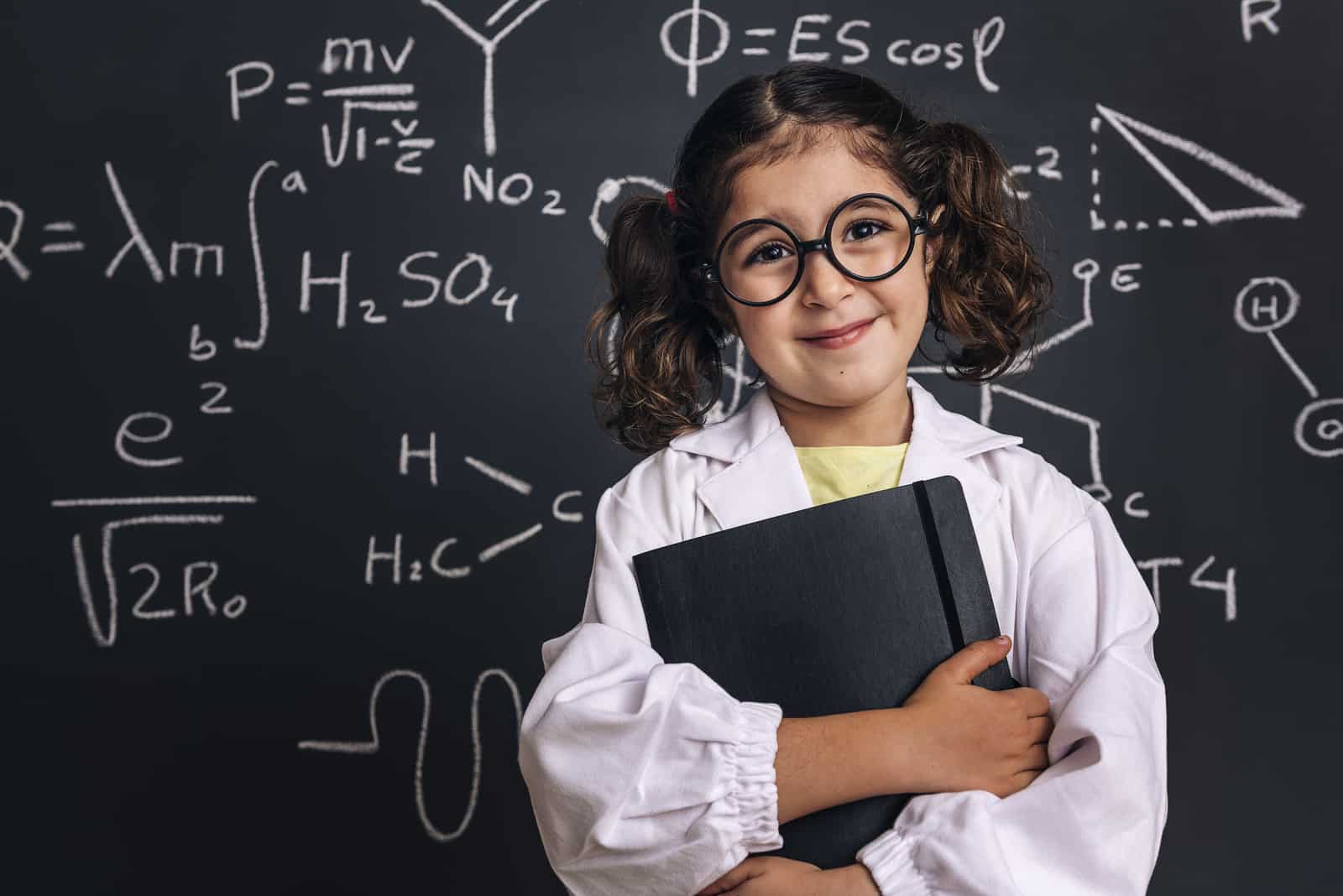 smiling little girl in lab coat with a notebook