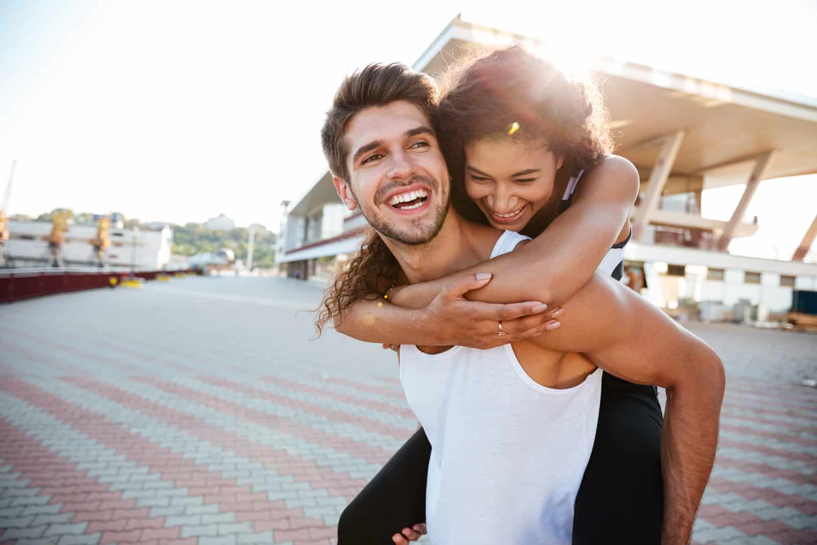 homem sorridente que carrega a namorada às costas 