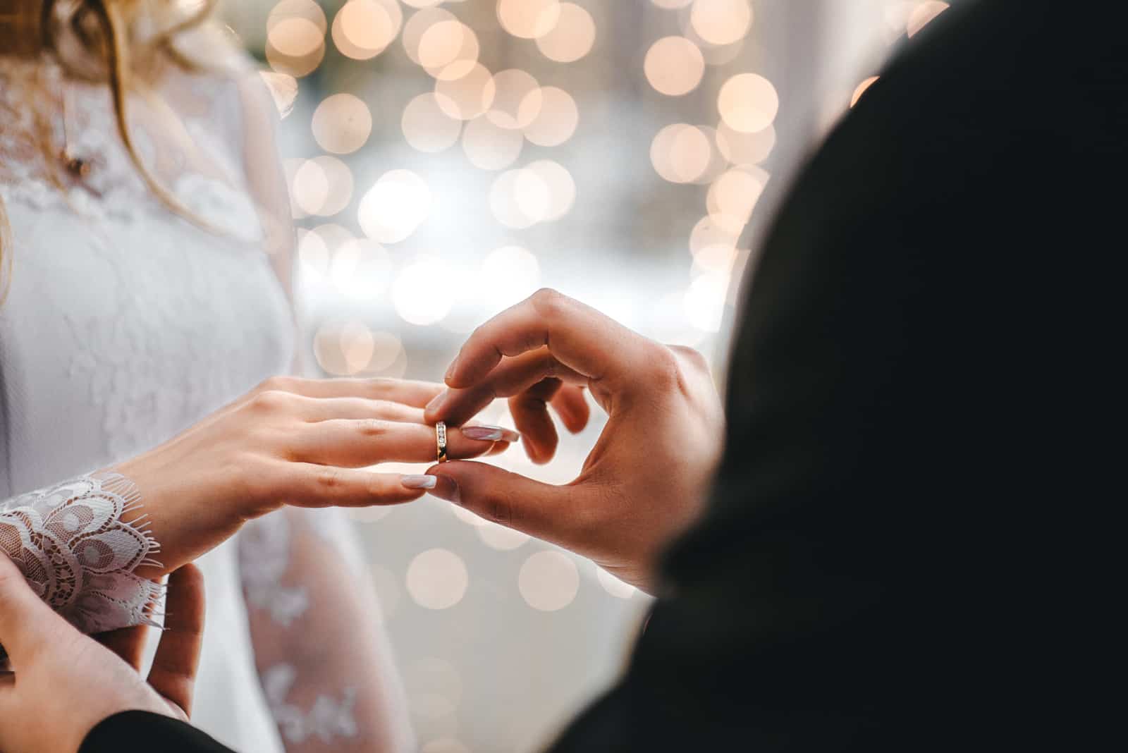 the groom putting a wedding ring on bride's finger
