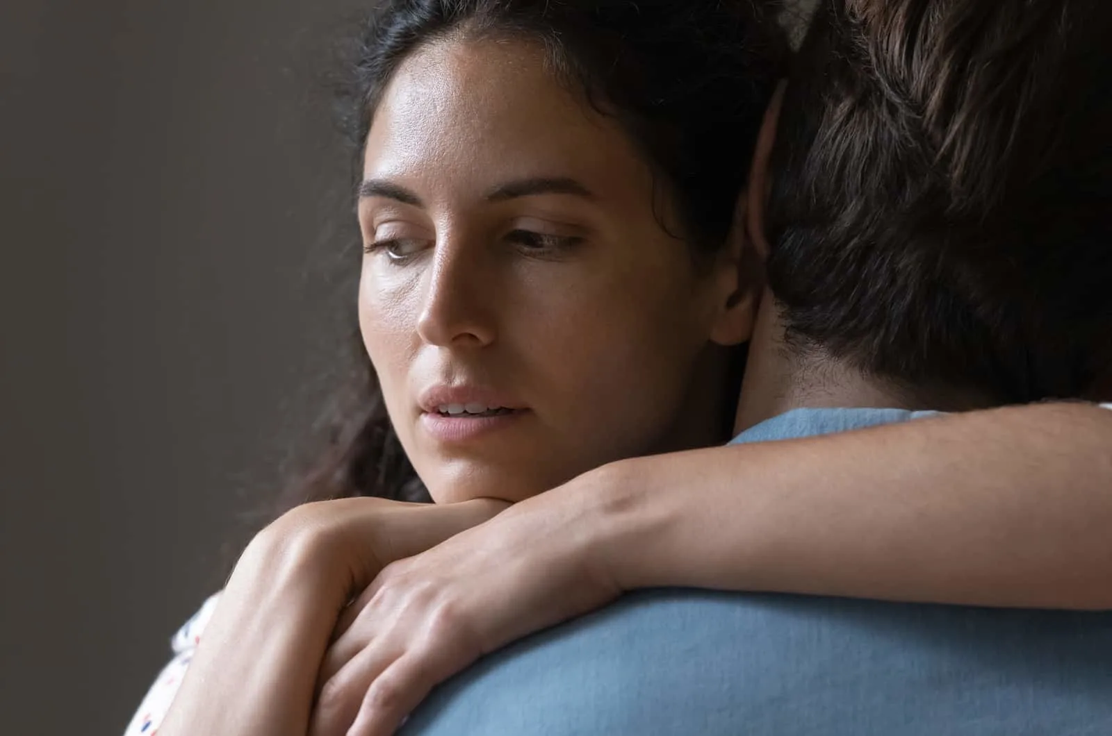 woman hugging her partner with a worried expression