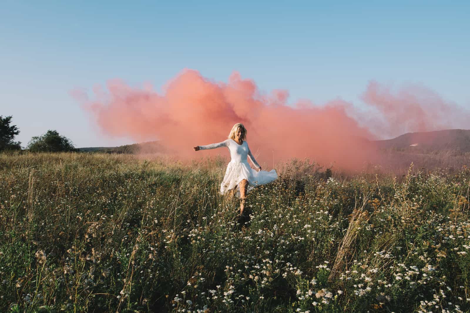 woman in field with pink smoke