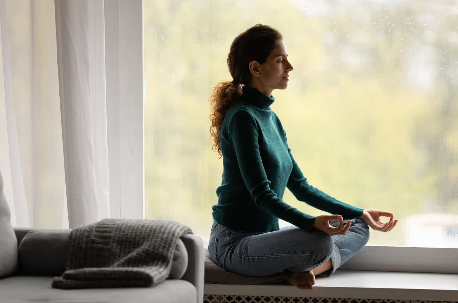 woman meditating in house by window
