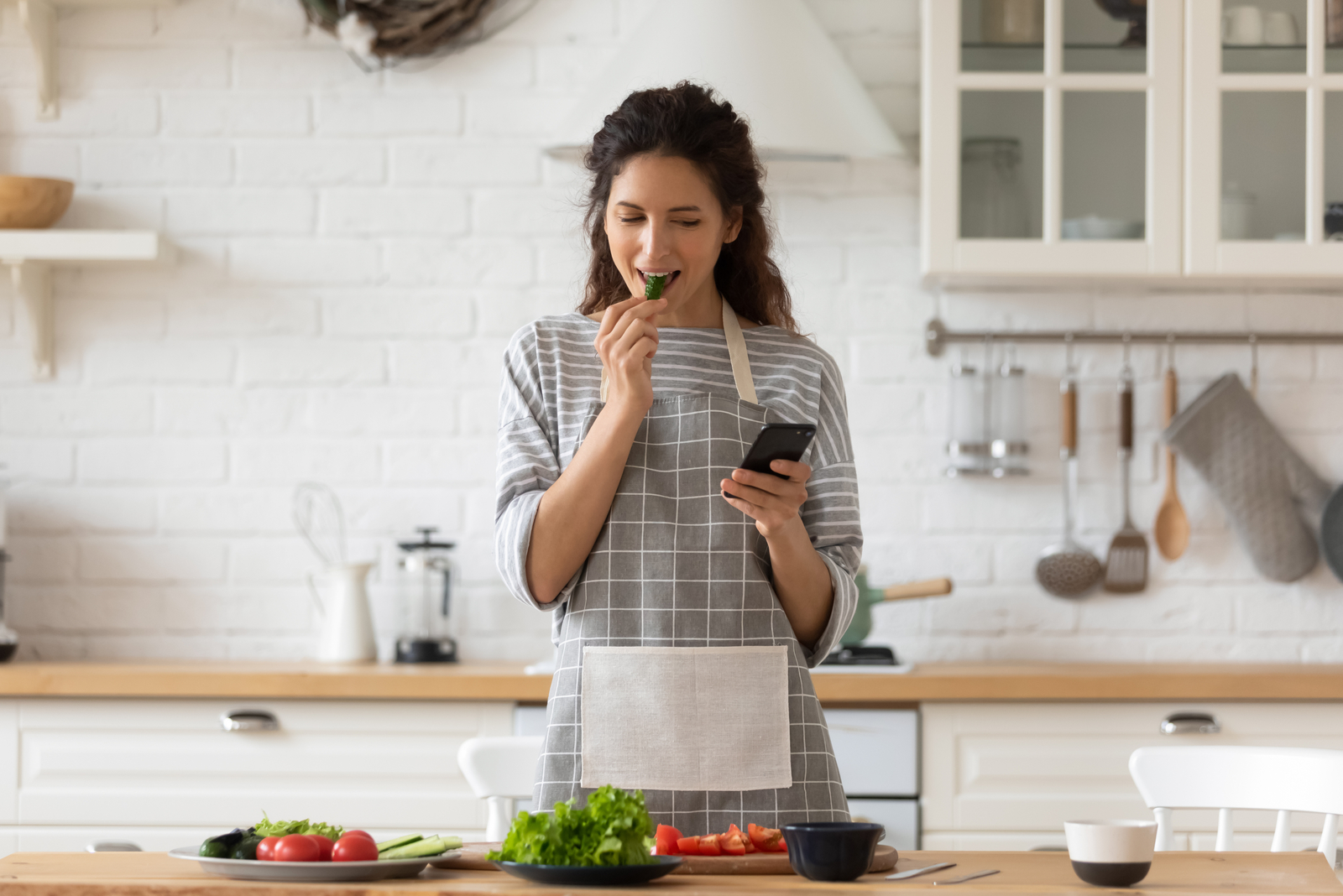 woman with phone in hand standing in kitchen