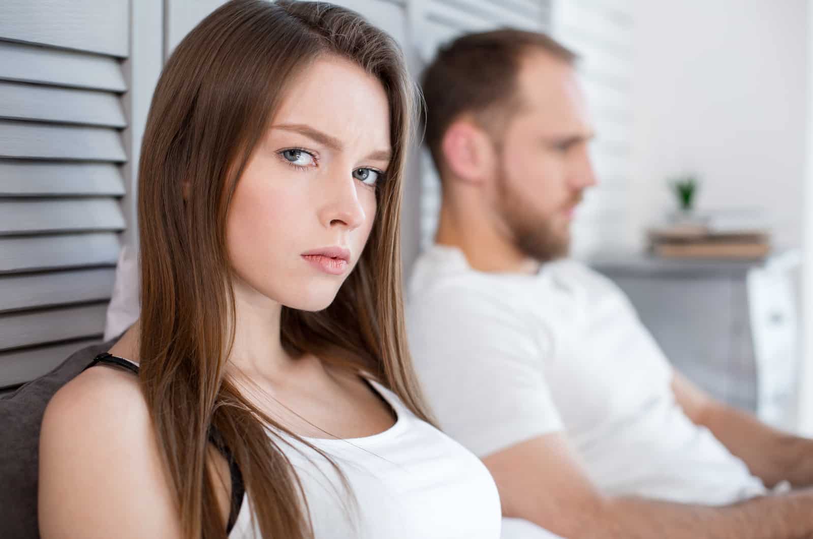 worried woman thinking while her boyfriend sits next to her