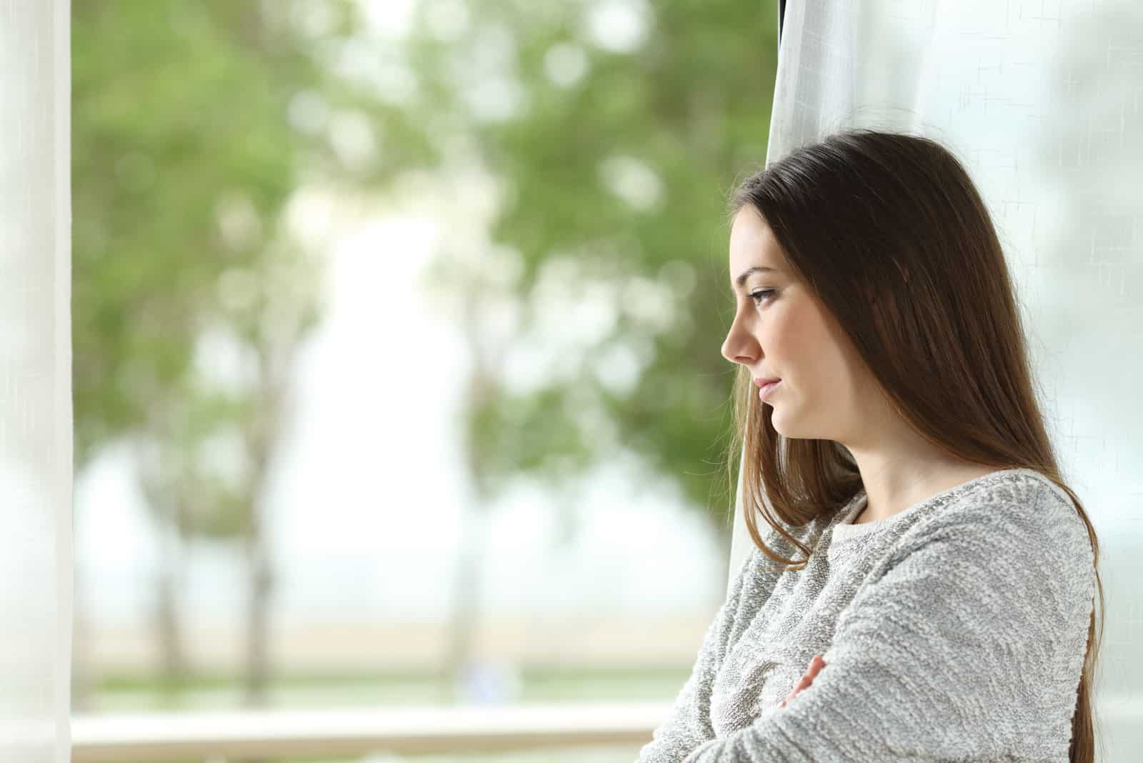 worried young woman standing by the window