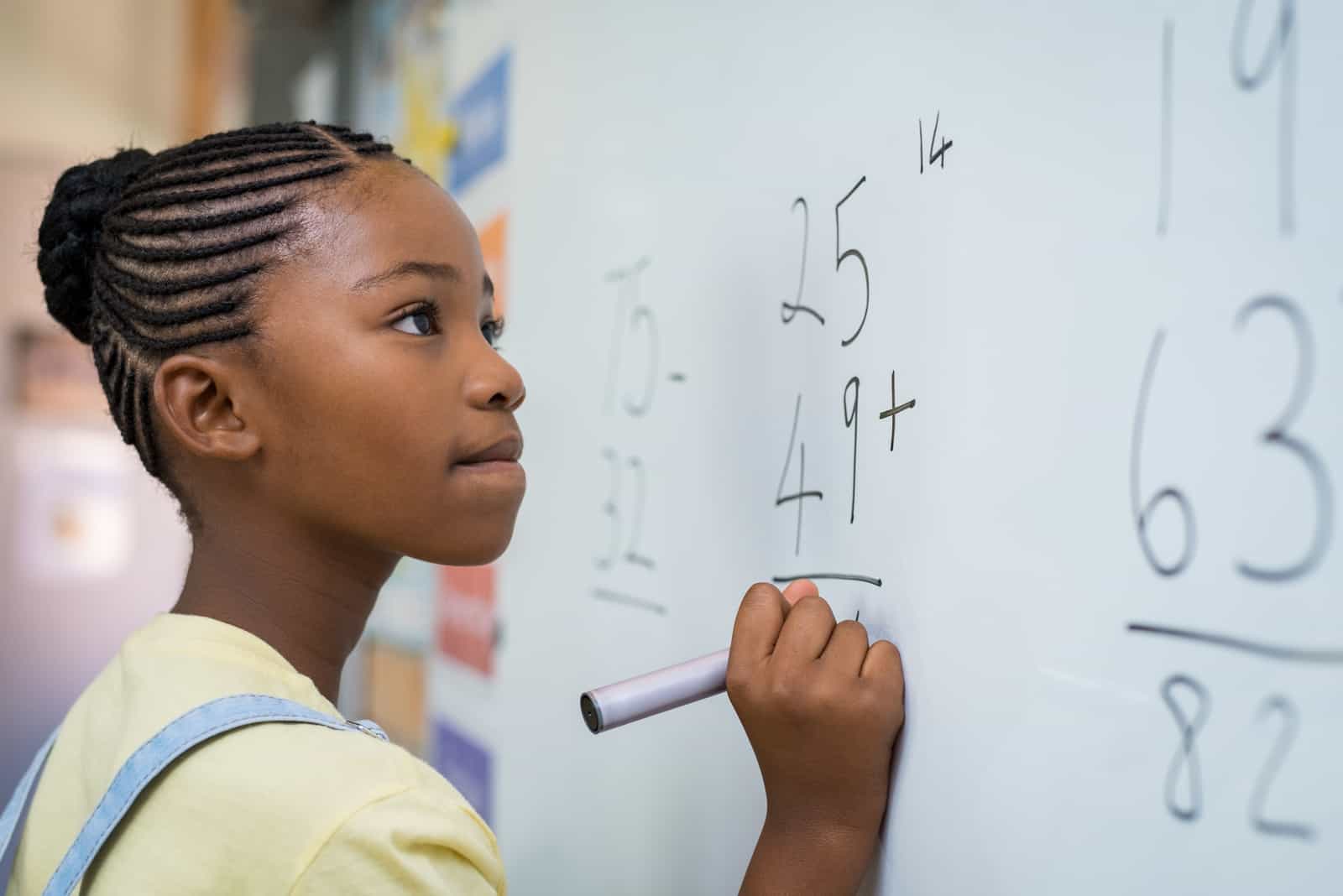 ragazza che scrive una somma di matematica alla lavagna