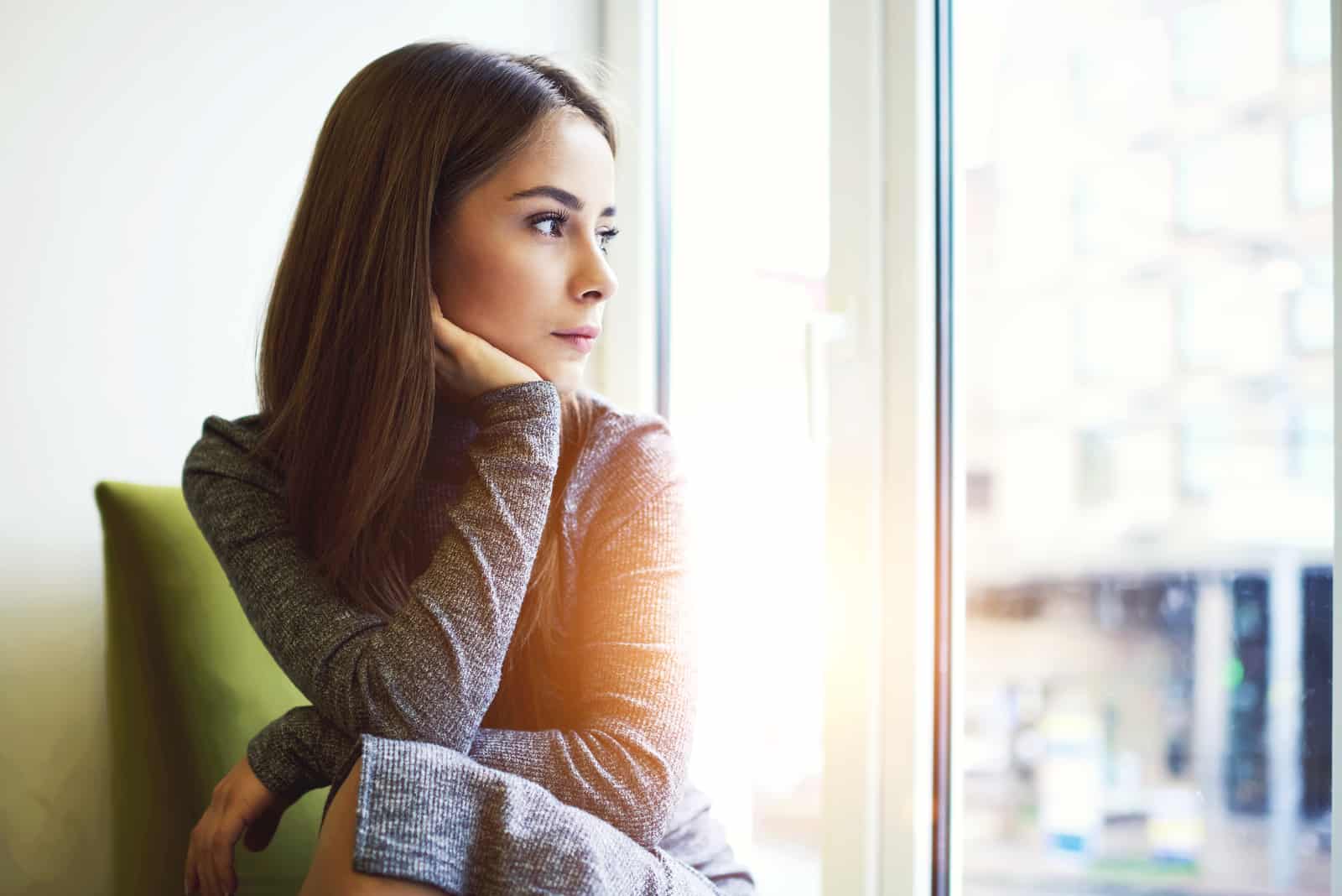 young mindful woman looking through the window