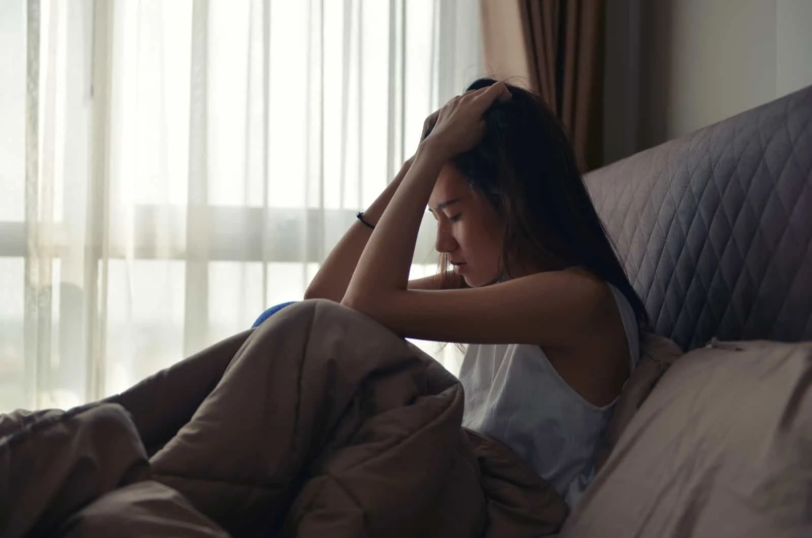 young woman crying in her bed because people only care about themselves 