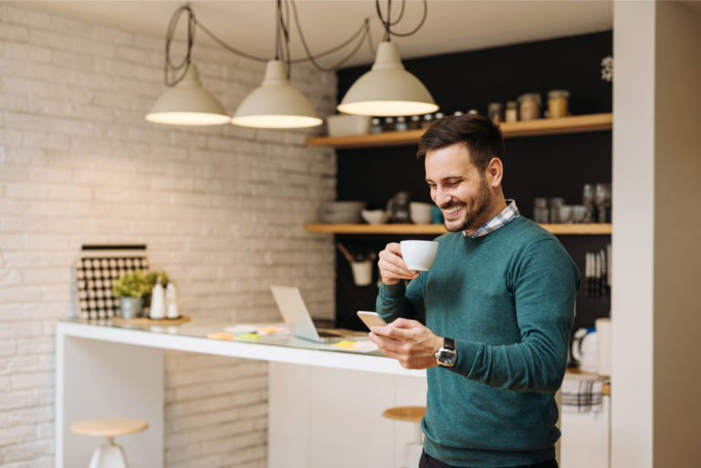 un hombre sonriente de pie en la cocina y botones en el teléfono