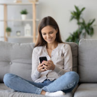 mulher sentada no sofá a enviar mensagens de texto