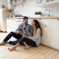 couple sitting on kitchen floor drinking wine