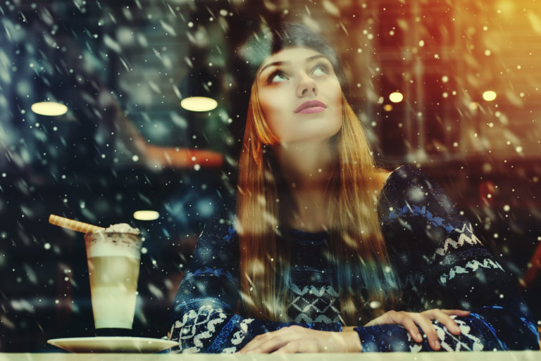 a beautiful woman with a hat on her head sits at a table and looks up at the sky