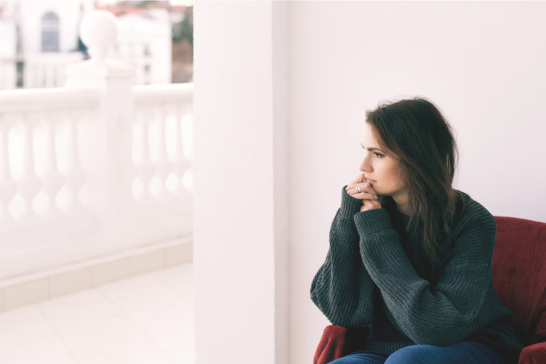 a sad woman sits on the sofa and looks away