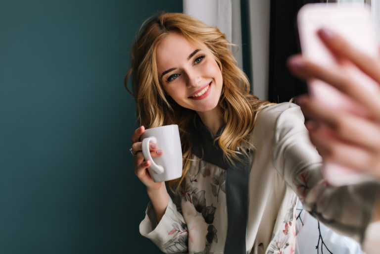 woman taking a selfie while holding a mug