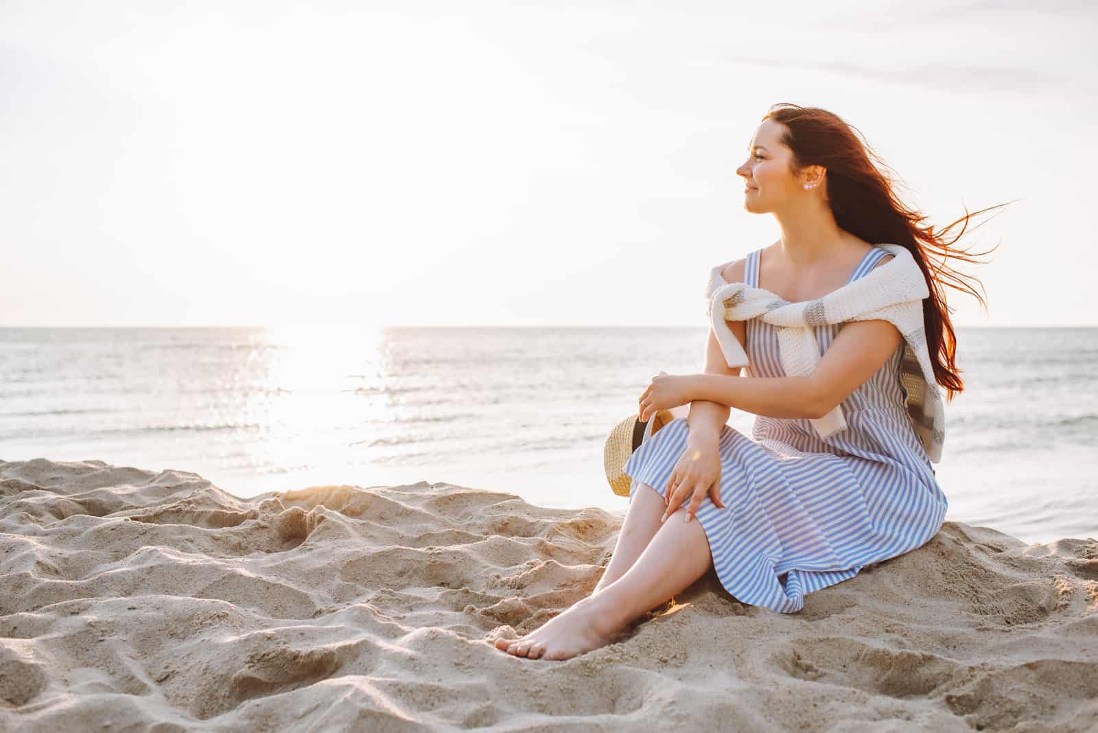 a beautiful woman sitting on the beach