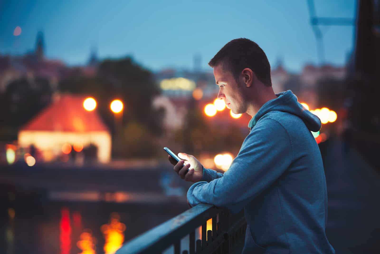 a man leaning against a railing button on the phone