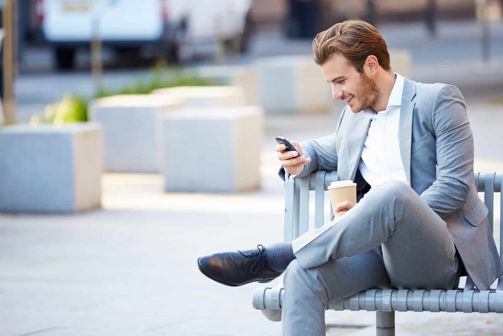 um homem sentado num banco e um botão no telefone