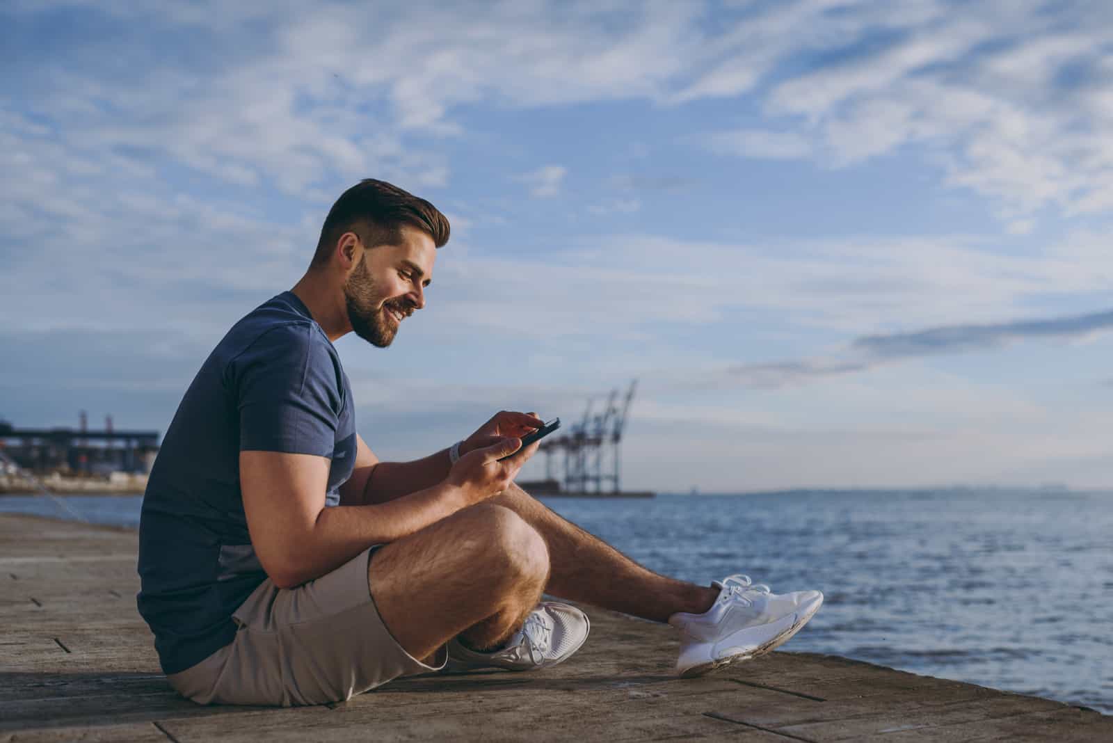 a man sits on the beach and buttons on the phone