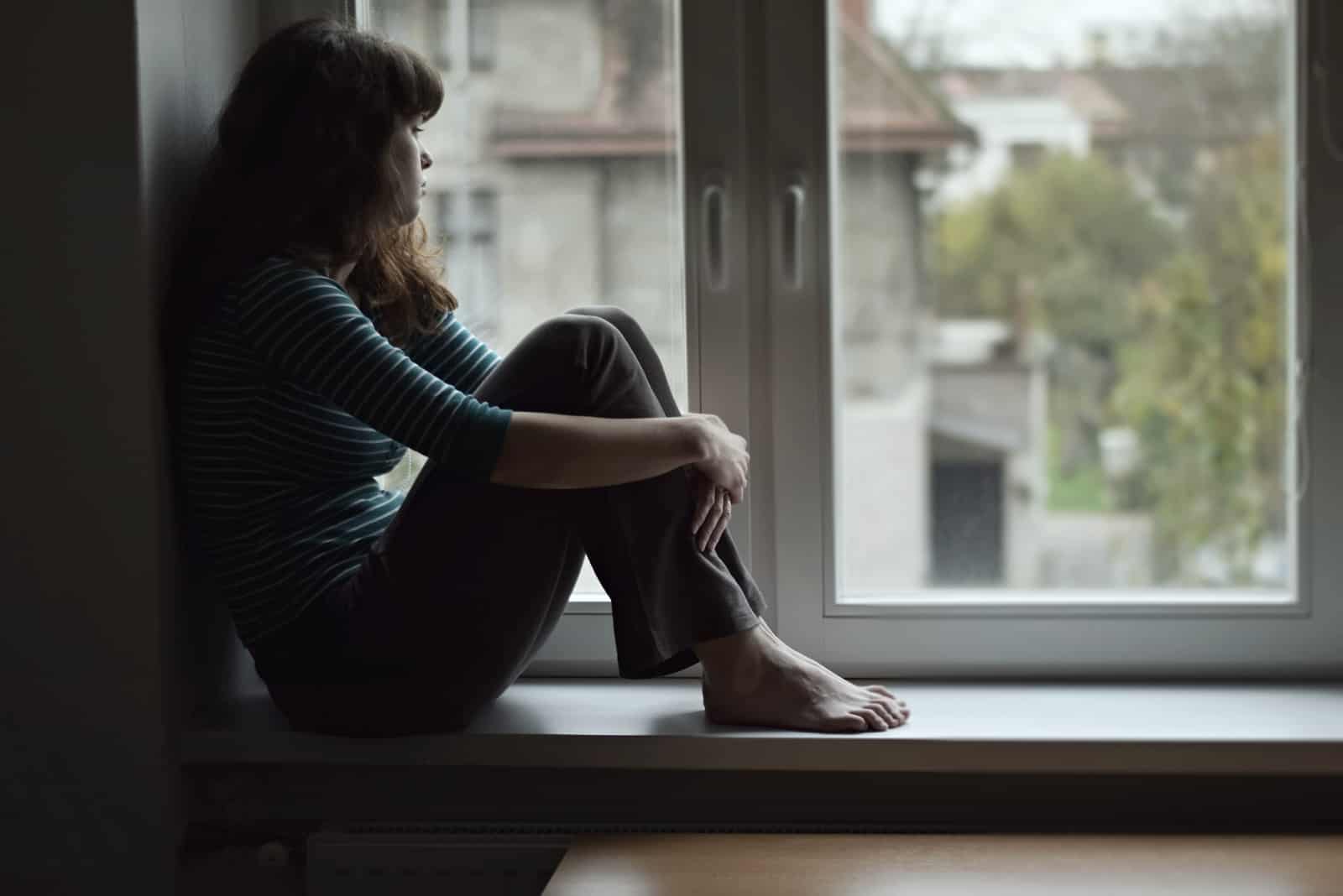 a sad woman sitting by the window