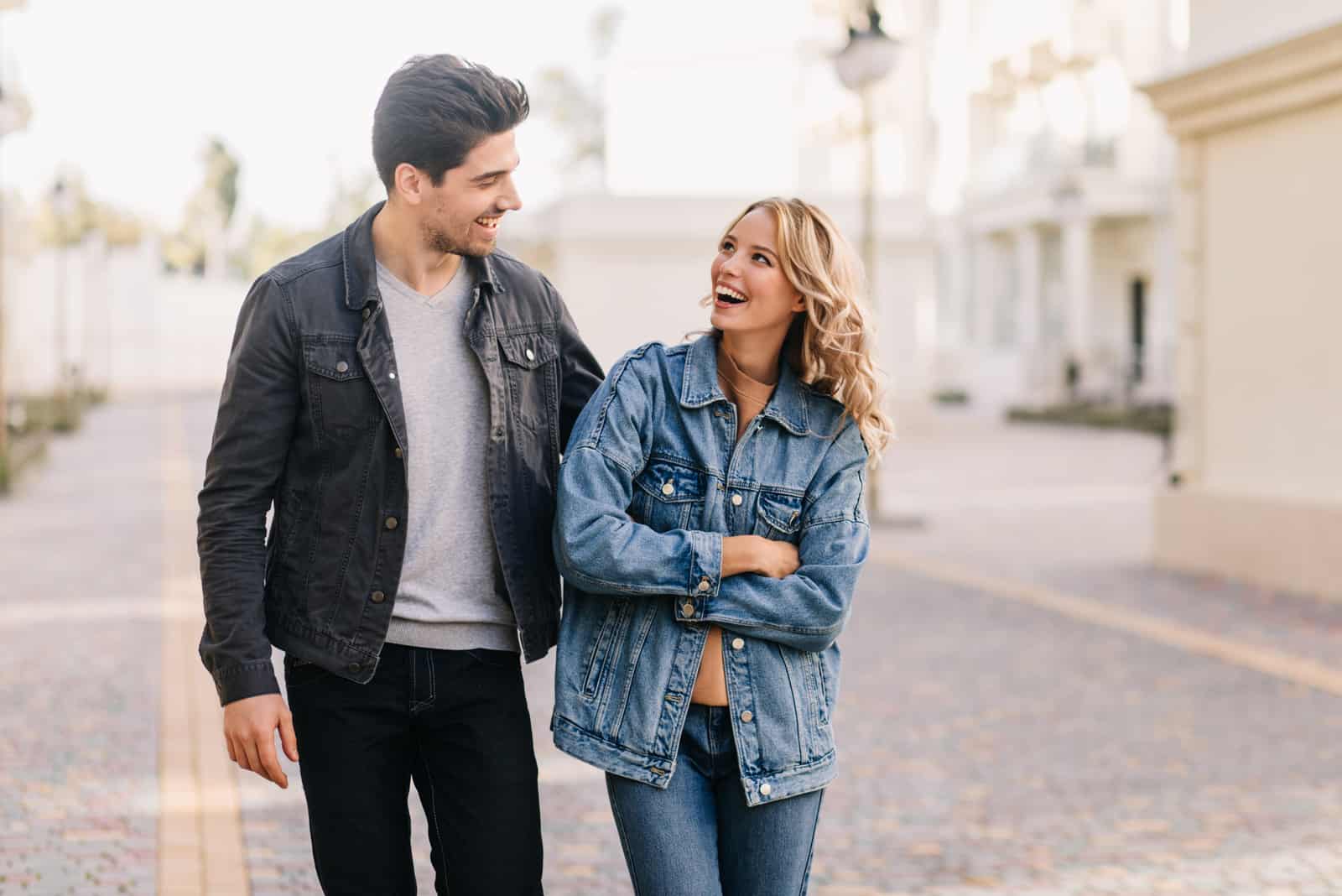 a smiling man and woman walking down the street