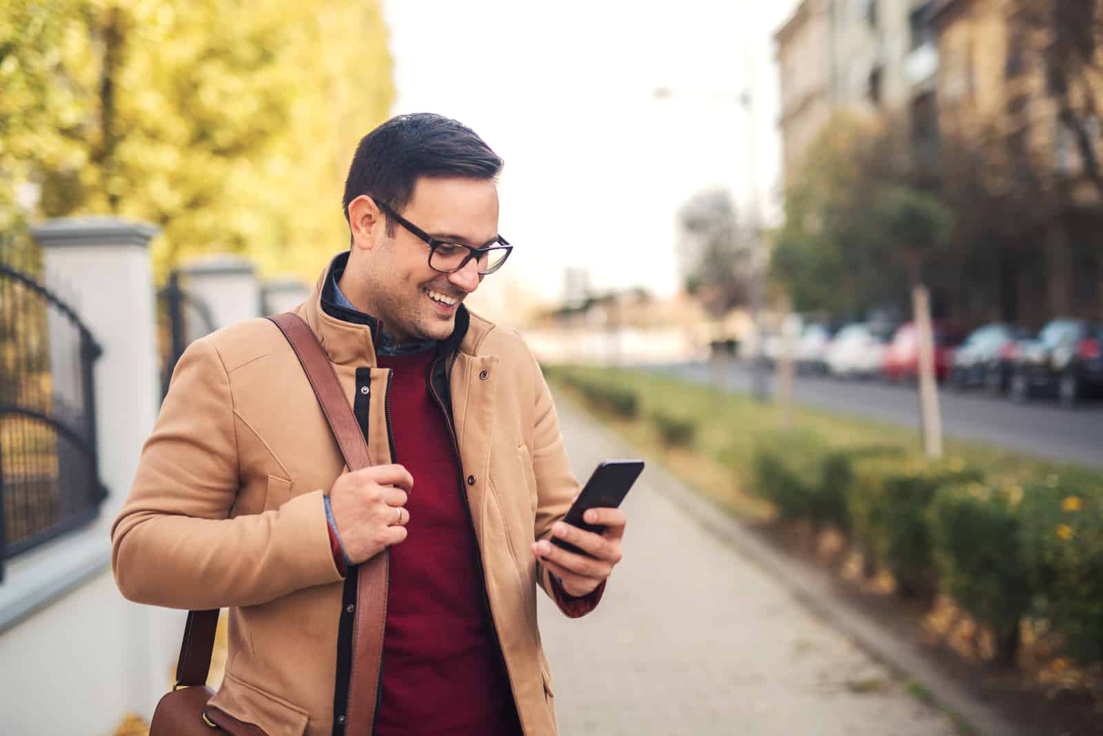 un uomo sorridente è in piedi per strada e telefona al telefono